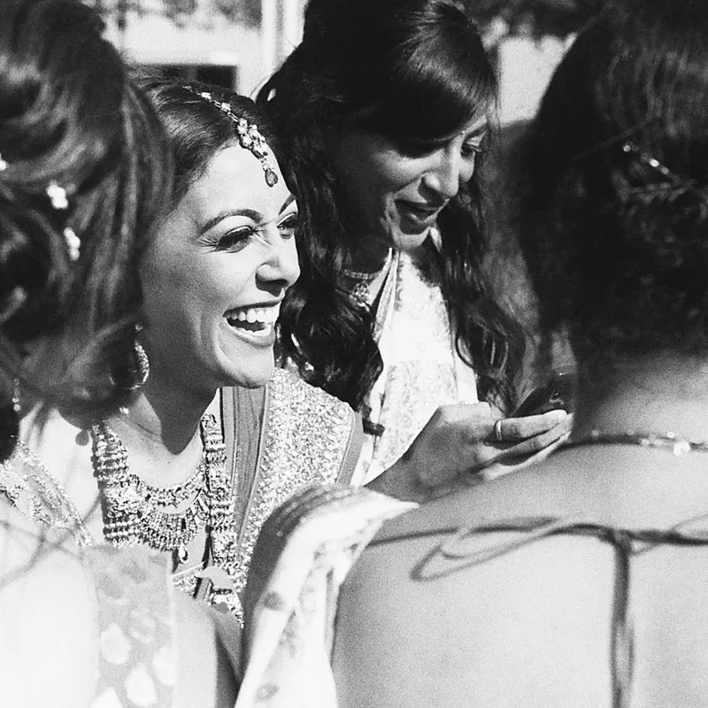 An Indian bride, laughing with her bridesmaids.