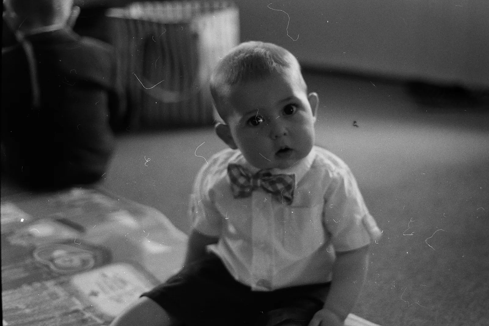 A fat little baby, looking at the camera with his head tilted.