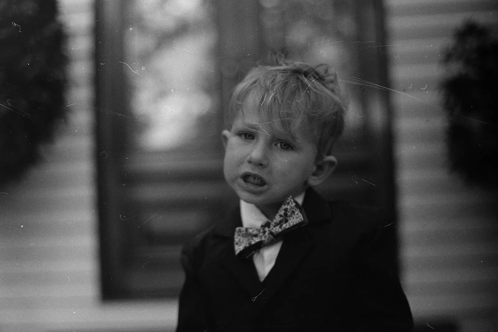 A boy with a crooked bowtie and messy hair.