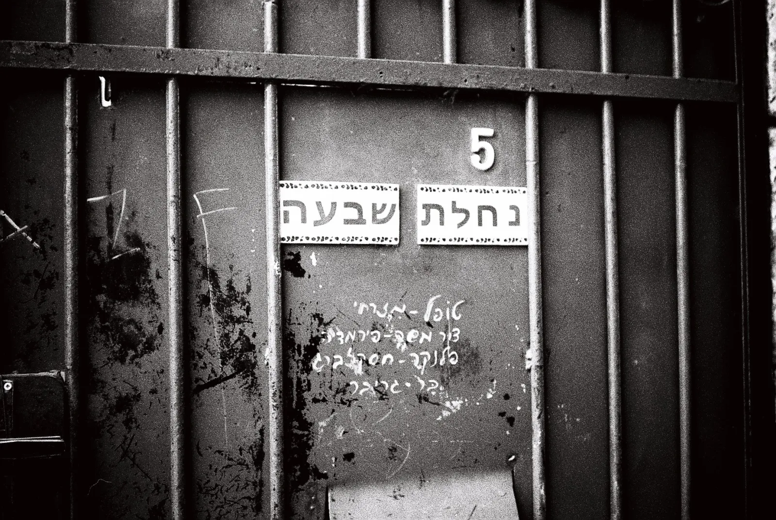 The front door of an apartment, with Hebrew handwriting, tiles, and the number 5.