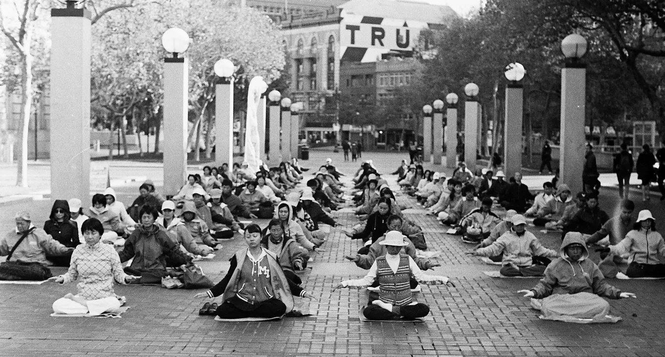 A group of people meditating in a city.